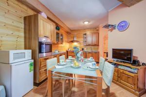 塞斯特雷Borgata Family Studio Ski In Ski Out 300m - Happy Rentals的厨房里有一张桌子、几把椅子和一台白色冰箱