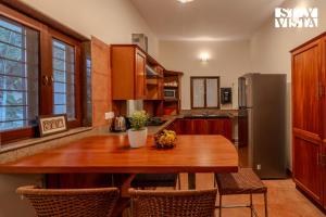 a kitchen with a wooden table and a refrigerator at StayVista at The Lakeshore with Lake View, WiFi, Garden in Bengaluru
