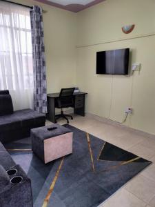 a living room with a couch and a table and a television at KAJIADOHOMES in Kajiado +6 photos