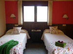 due letti in una stanza con pareti rosse e una finestra di Casa Rural Don Romualdo a Casar de Palomero