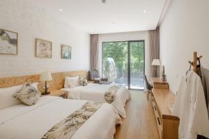 una camera d'albergo con due letti e un balcone di Vretreats yunxishang Boutique Hotel a Deqing