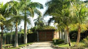 a garage with palm trees and a driveway at Espaço Sorrentino's in Itupeva