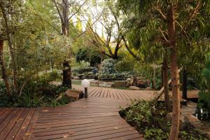 een houten loopbrug in een park met een lamp erop bij Jedidja Bed and Breakfast in Bloemfontein