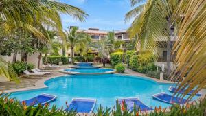 a pool with blue chairs and palm trees at Sunshine Escape with a Rooftop Patio in Coco