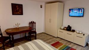 a bedroom with a bed and a desk and a tv on the wall at Casa Teo in Buzău