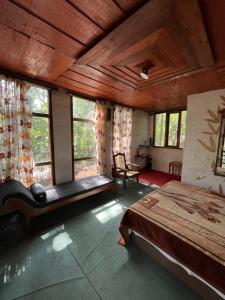a bedroom with a bed and a bench and windows at Whitetea Estatehouse Tree House in Munnar