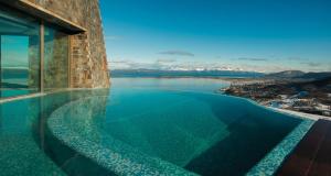 a infinity pool with a view of the water at Arakur Ushuaia Resort & Spa in Ushuaia