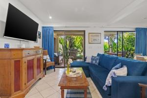 a living room with a blue couch and a tv at Sunshine Escape with a Rooftop Patio in Coco