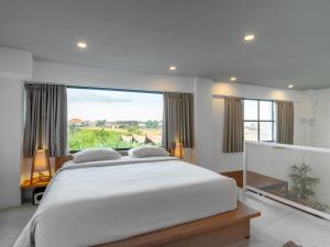 Un dormitorio con una cama grande y una ventana grande. en Tropicana Loft Canggu, en Canggu
