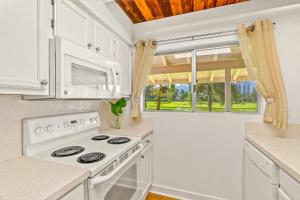 a kitchen with white appliances and a large window at Beautiful Airy 1 Br Condo with Loft Golf Course View Pool Hot tub 209A in Princeville