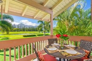 a table on a balcony with a view of a golf course at Beautiful Airy 1 Br Condo with Loft Golf Course View Pool Hot tub 209A in Princeville