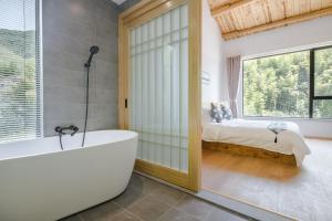 un bagno con vasca e una camera da letto con un letto di Vretreats yunxishang Boutique Hotel a Deqing