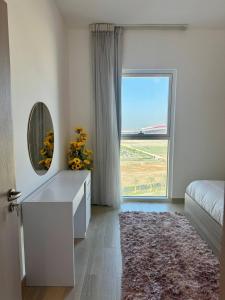 a bedroom with a large window and a dresser with a mirror at Canal & Marina View 1br High Floor Pool & Gym in Abu Dhabi +15 photos