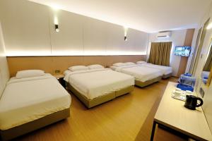 a hotel room with three beds and a television at Ming Paragon Hotel in Kuala Terengganu +31 photos