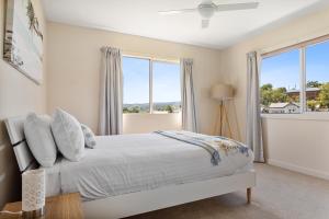 a white bedroom with a bed and windows at Tokenburg Townhouse in Launceston