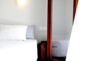 Steni Vala AlonissosにあるCasa Kalypso Suites & Villaのベッドルーム(白いベッド1台、鏡付)