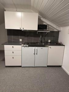 a kitchen with white cabinets and a black counter top at Stor hybel in Tromsø