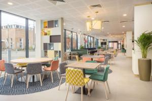 纽尼顿Hampton By Hilton Nuneaton的自助餐厅内带桌椅的等候区