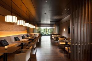 a restaurant with wooden tables and chairs and lights at Hilton Kyoto in Kyoto