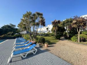 a row of blue lounge chairs next to a pool at Westhill Country Hotel in Saint Helier Jersey