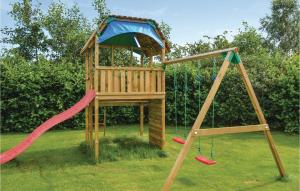 a wooden playground with a swing and a slide at Four-Bedroom Holiday Home In Storvorde in Storvorde