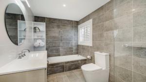 a bathroom with a toilet and a sink and a mirror at Beach Bliss - Umina Beach in Umina Beach 
