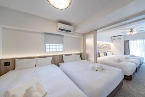 3 posti letto in una stanza con lenzuola bianche di Apartment Hotel 11 Namba Motomachi ad Osaka