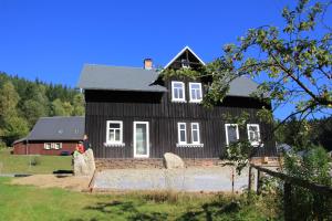 uma mulher em frente a uma casa negra em Fw. Glashütte Anno Dazumal em Klingenthal