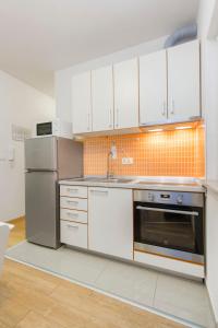 cocina con armarios blancos y nevera de acero inoxidable en Apartments Srdarev Pencov, en Vodice