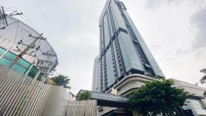a tall building with a sign in front of it at Lavish 2BR Apartment at Grand Sungkono Lagoon By Travelio in Surabaya