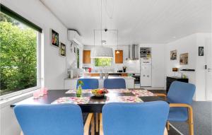 a kitchen and dining room with a table and blue chairs at Holiday Home Syrenvej Ebeltoft I in Øksenmølle