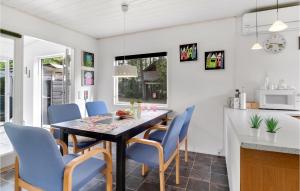 a kitchen and dining room with a table and blue chairs at Holiday Home Syrenvej Ebeltoft I in Øksenmølle