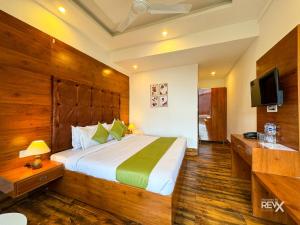 una camera con un grande letto e una televisione di Hotel Wraveler Inn Mussoorie a Mussoorie
