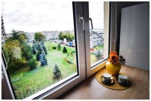 a window with a vase and cups on a table at Color 24 Apartament VIII in Stalowa Wola