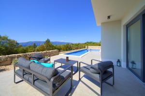 Un patio con mesa y sillas y una piscina. en Villa Aurum with sauna and gym, en Krk