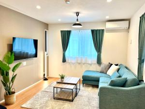 a living room with a blue couch and a tv at Casa Stella 4 by Liaison in Osaka