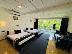 una camera da letto con due letti e una TV a schermo piatto di Forest Dew Udawalawa a Udawalawe