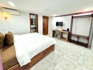 a bedroom with a bed and a desk and a television at The Cozy Corner-Budget Hotel in Phumĭ Kâmpóng Kândal