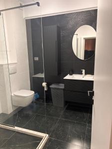 ein Badezimmer mit Toilette, Waschbecken und Spiegel in der Unterkunft Apartament Wave5 in Năvodari