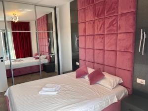 Zimmer mit einem Bett mit einer rosa Wand in der Unterkunft Apartament Wave5 in Năvodari