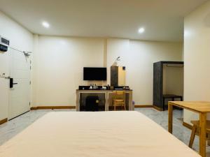 a room with a bed and a desk with a television at Wiang Kham Resort in Ban Na Phra That