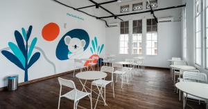 a room with tables and chairs in front of a mural at Bobopod Kota Tua, Jakarta in Jakarta