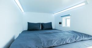 a bed in a white room with a window at Bobopod Kota Tua, Jakarta in Jakarta