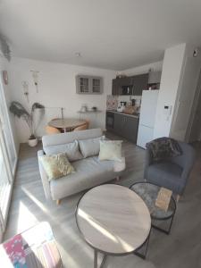 Una sala de estar con un sofá y dos sillas y una mesa. en Appartement récent tout confort, en Caen