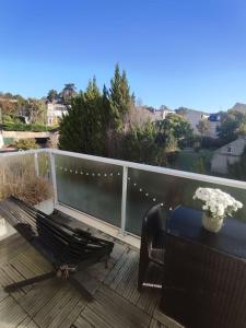 una terraza de madera con un banco y un jarrón de flores en Appartement récent tout confort, en Caen