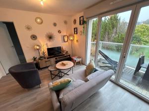 Una sala de estar con un sofá y una ventana grande. en Appartement récent tout confort, en Caen 5 fotos más