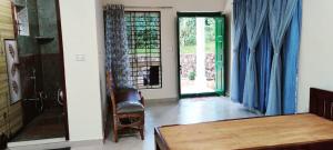 a living room with blue curtains and a table and a chair at Malnad Bliss in Sringeri