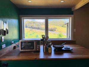 a microwave sitting on a wooden counter with a window at The Woolshed, Papa Aroha, Coromandel in Moturua Island