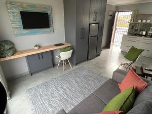 a living room with a couch and a tv on a wall at Tranquility - walking distance to beach in Langebaan