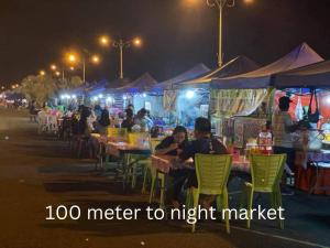 people sitting at tables at an outdoor market at night at homestay tawau kuhara court in Tawau